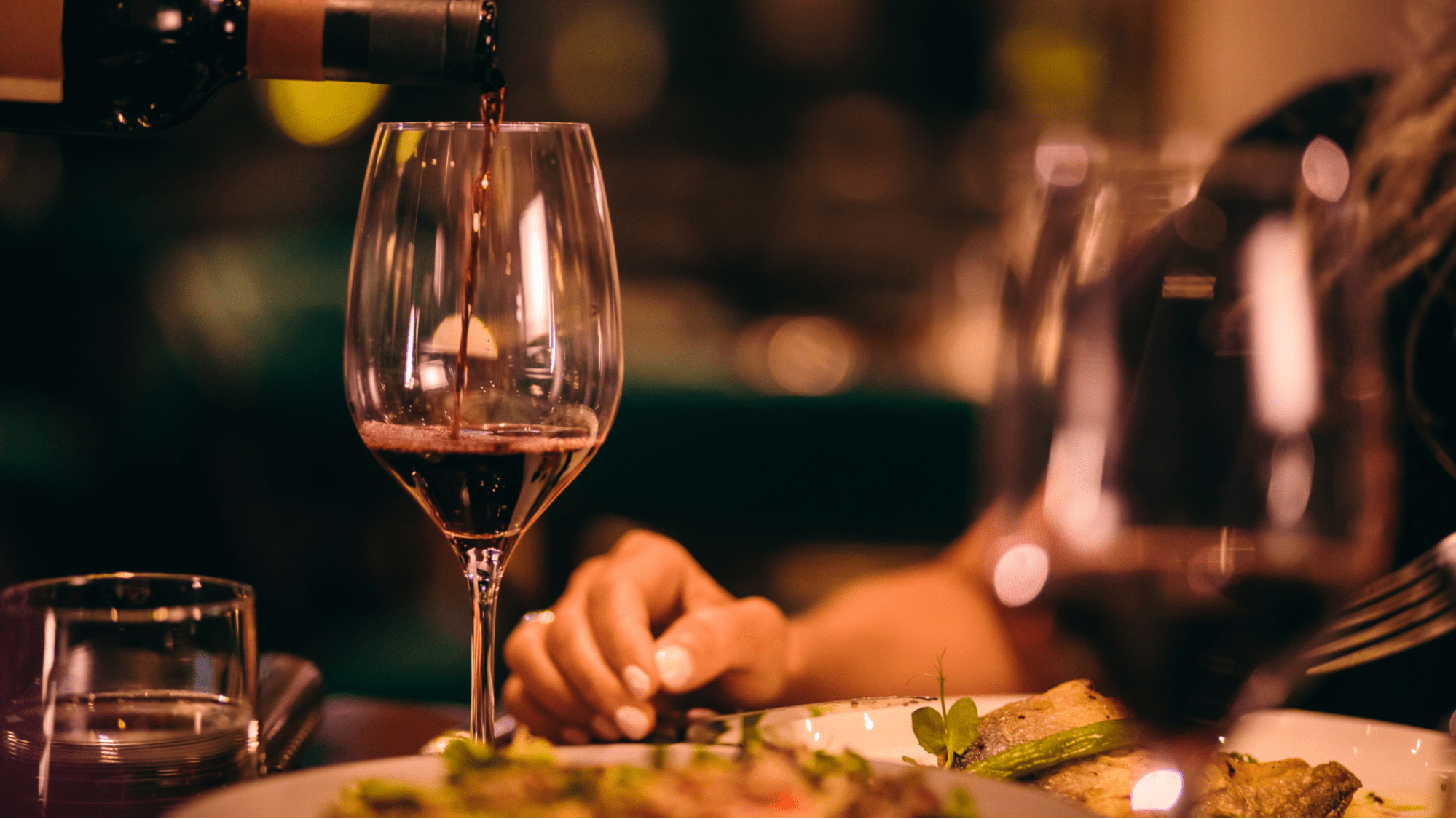 Glass of wine being poured at a dinner table